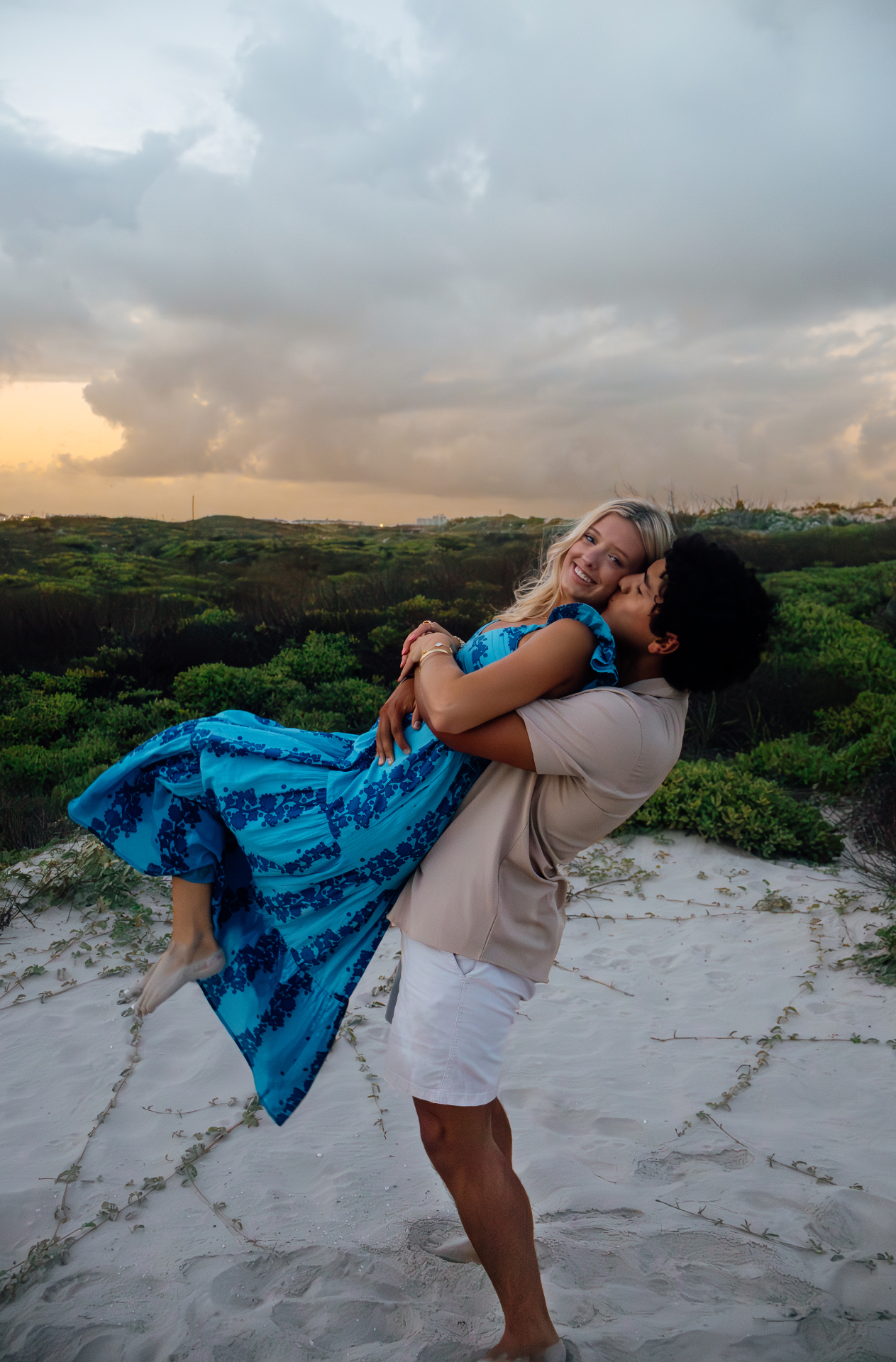 Couple embracing on the dunes at sunset